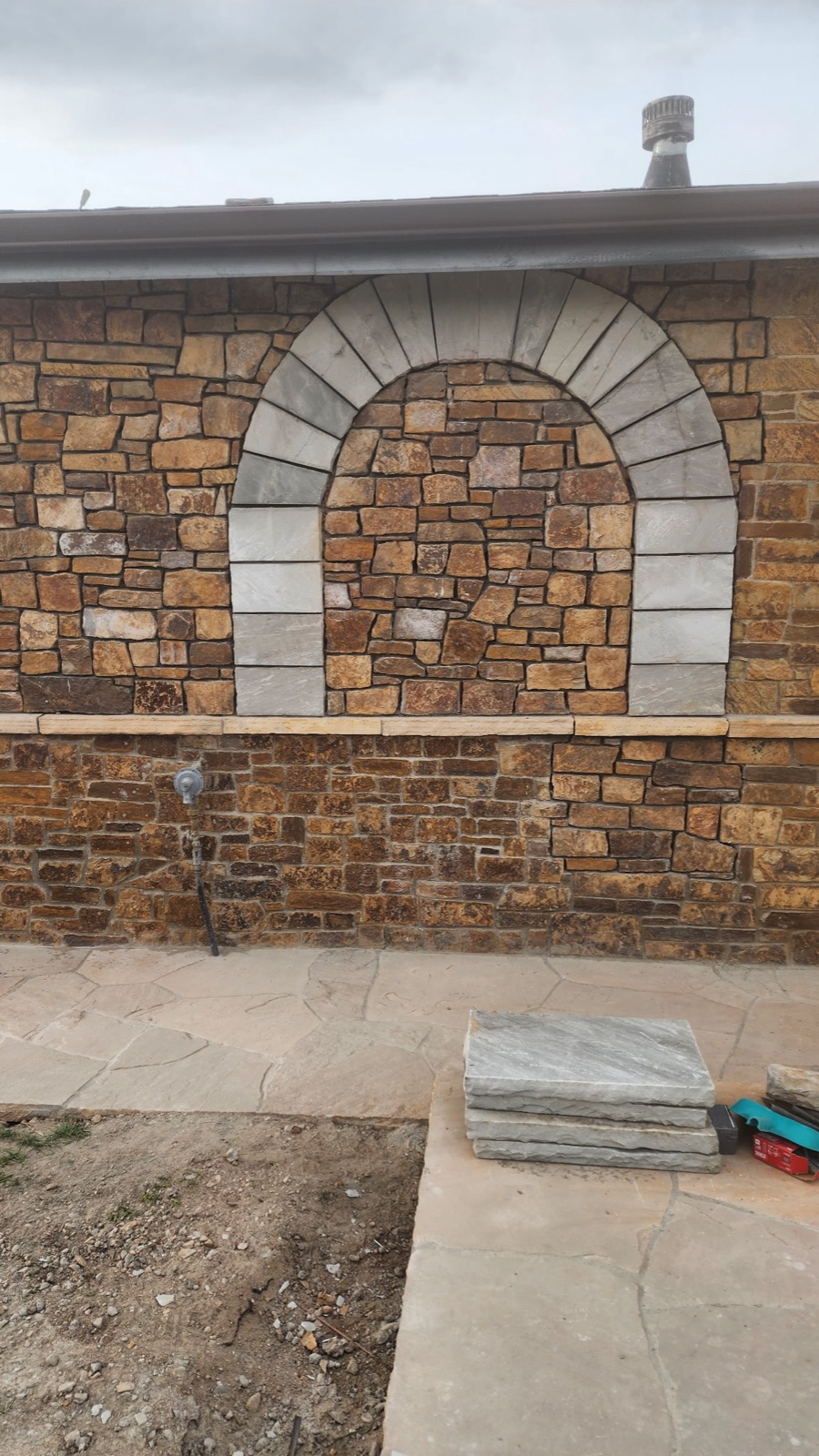 White sandstone arch detail set in a multicolor stone veneer wall