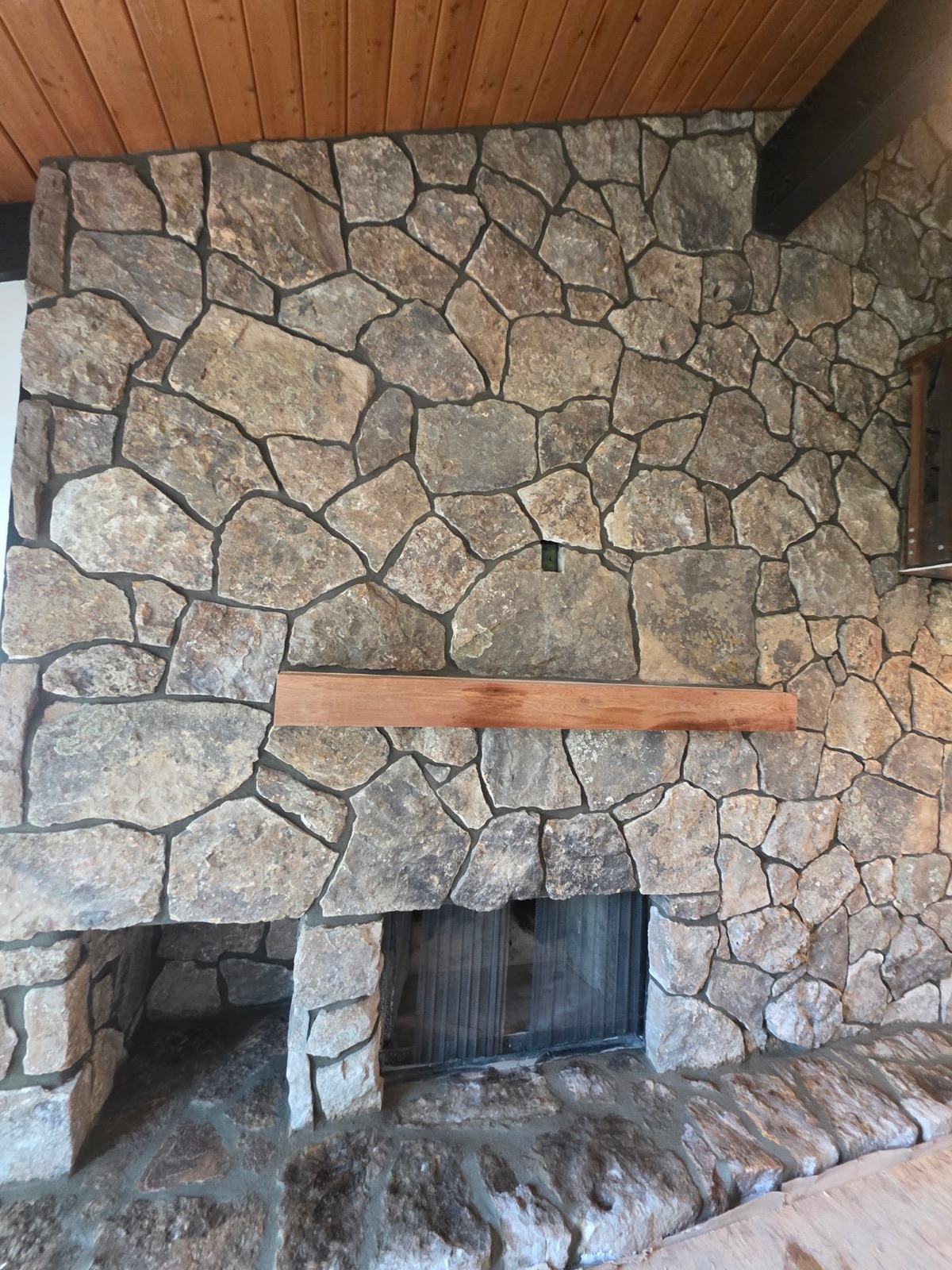 Moss-rock stone fireplace with timber mantel in a log home great room
