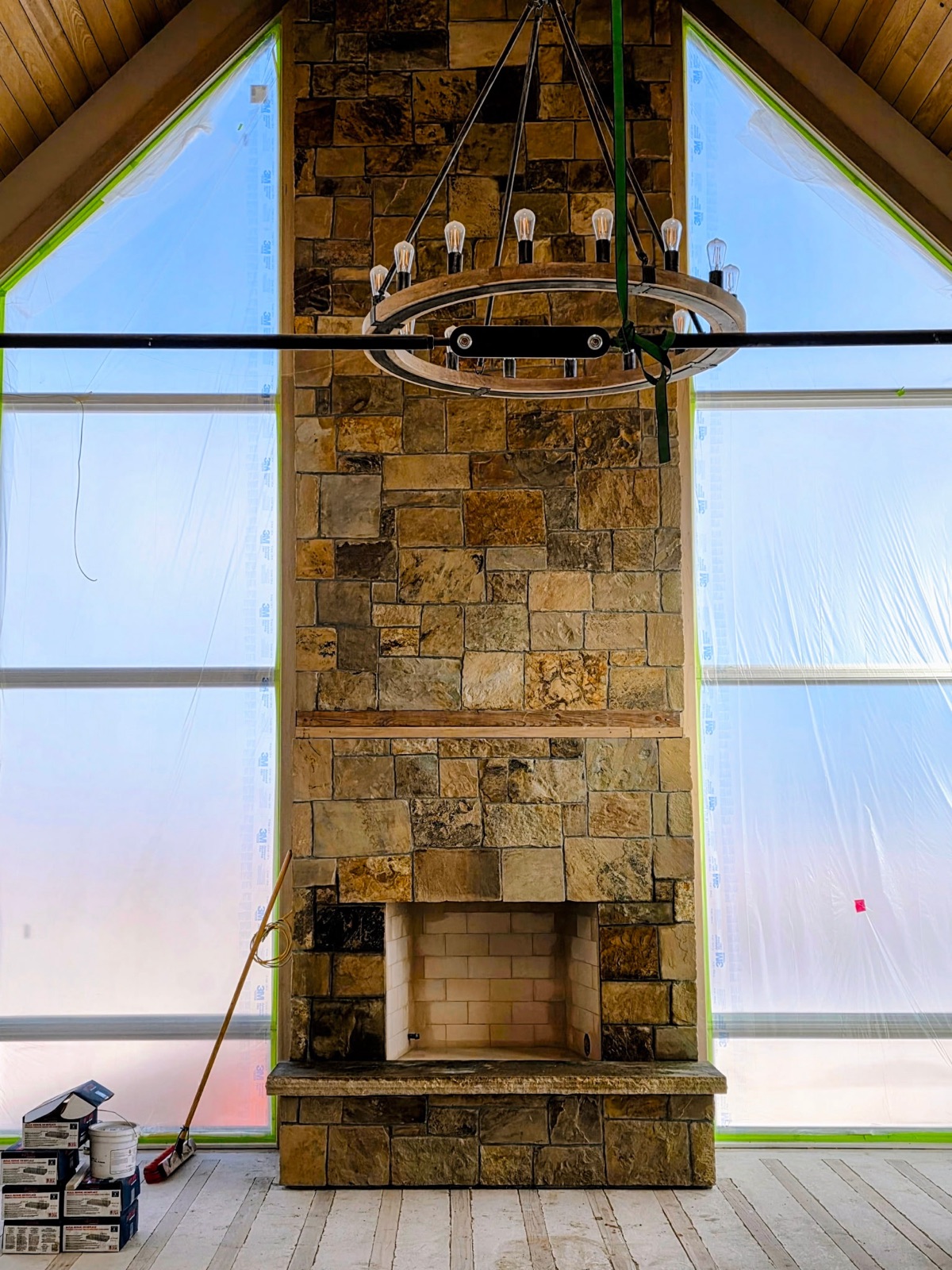 Two-story stone fireplace chase rising between A-frame windows