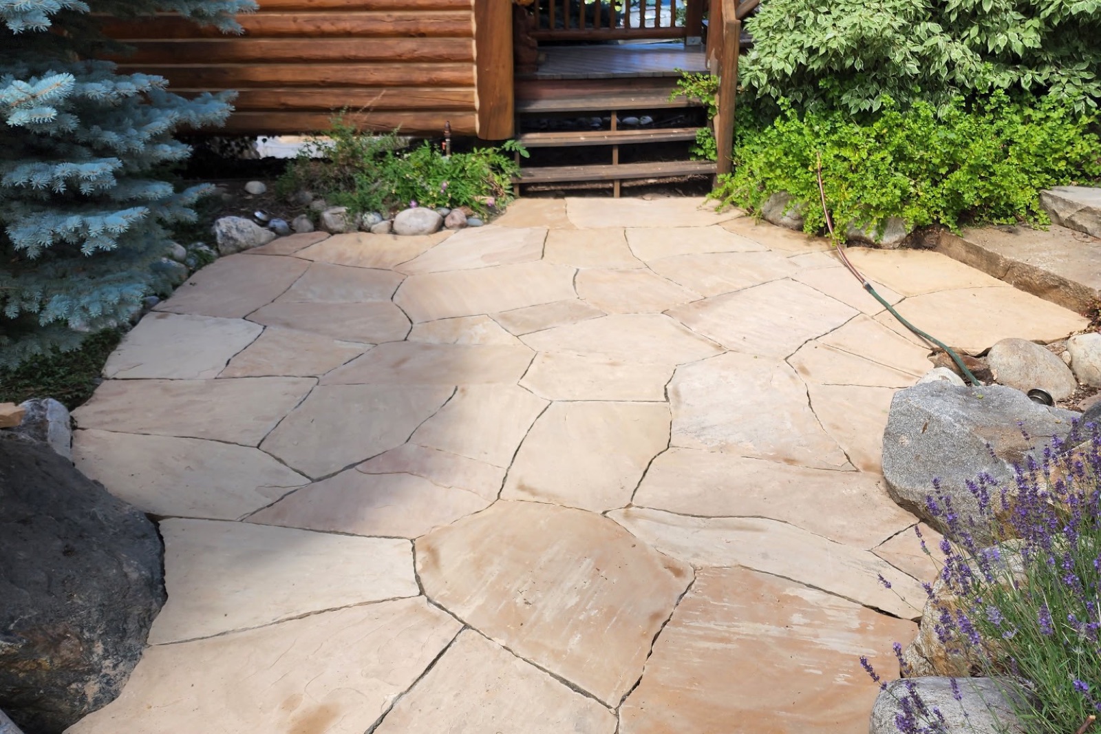 Flagstone patio with boulder edging at a log home