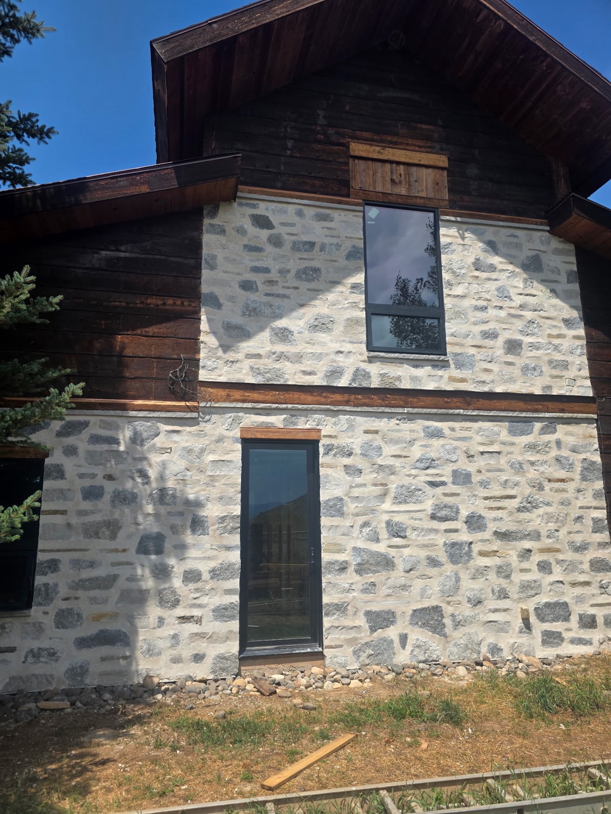 Finished granite stone veneer on a timber-and-stone home exterior