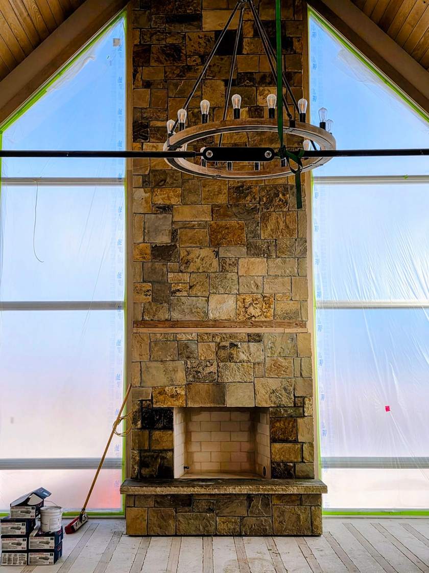 Two-story stone fireplace chase rising between A-frame windows