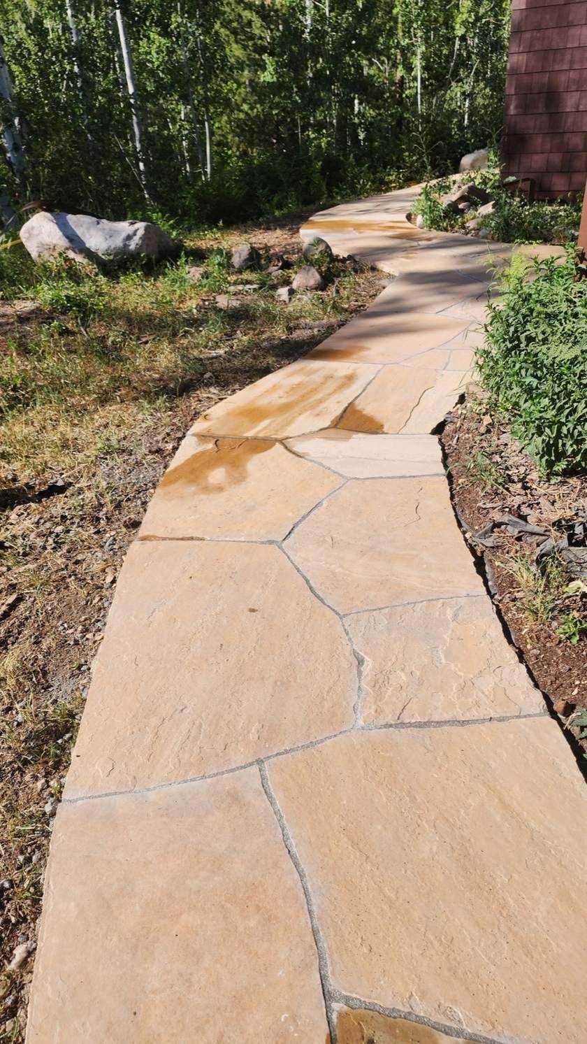 Winding flagstone path through aspens with river-rock edging