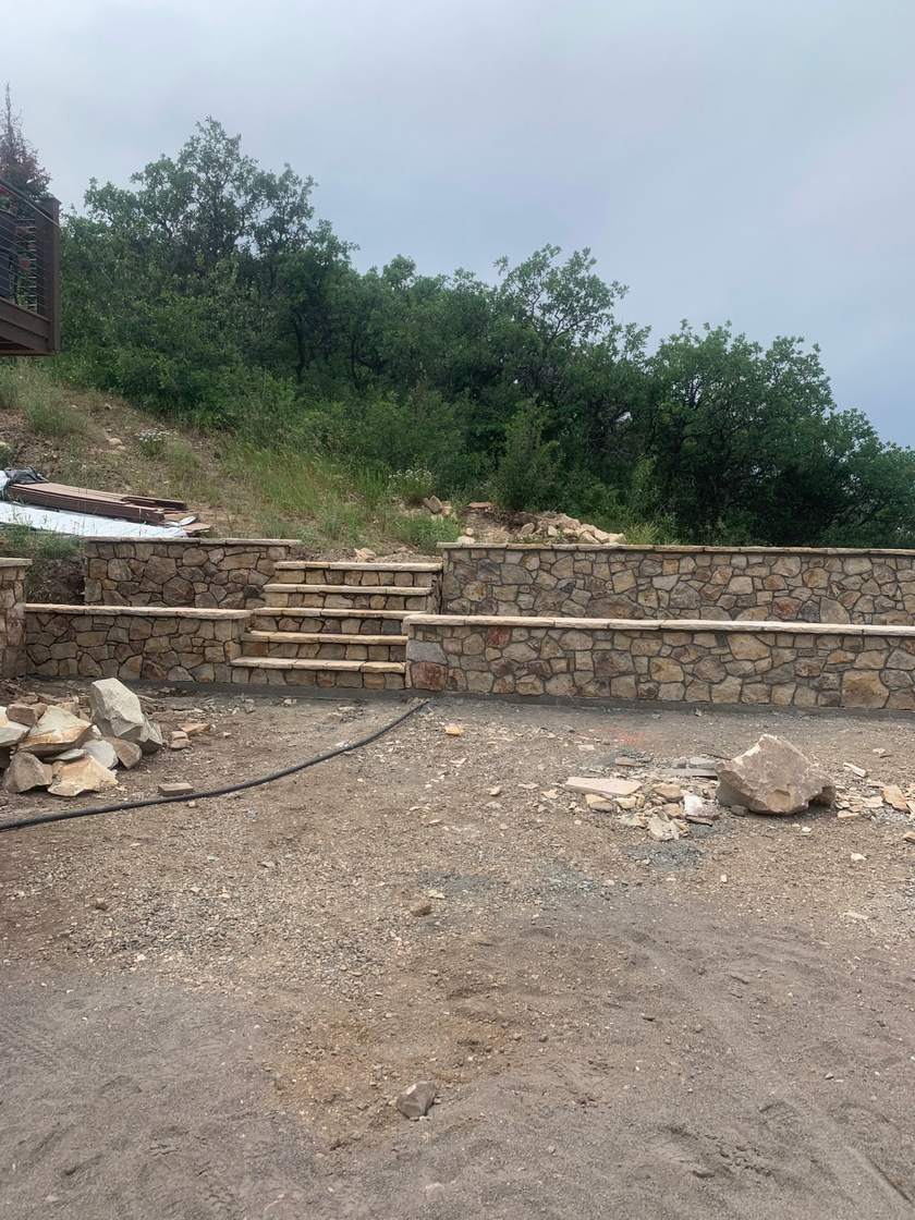 Terraced stone retaining walls with integrated stone stairs on a hillside